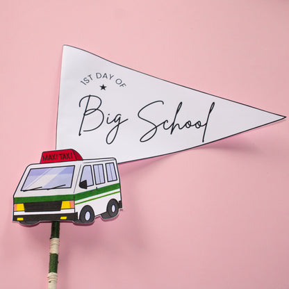 Pennant flag with '1st Day of Big School' text and a maxi taxi illustration on a pink background