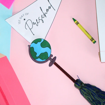 Decorative pennant flag with globe, crayon, and '1st Day of Preschool' sign on a colorful background